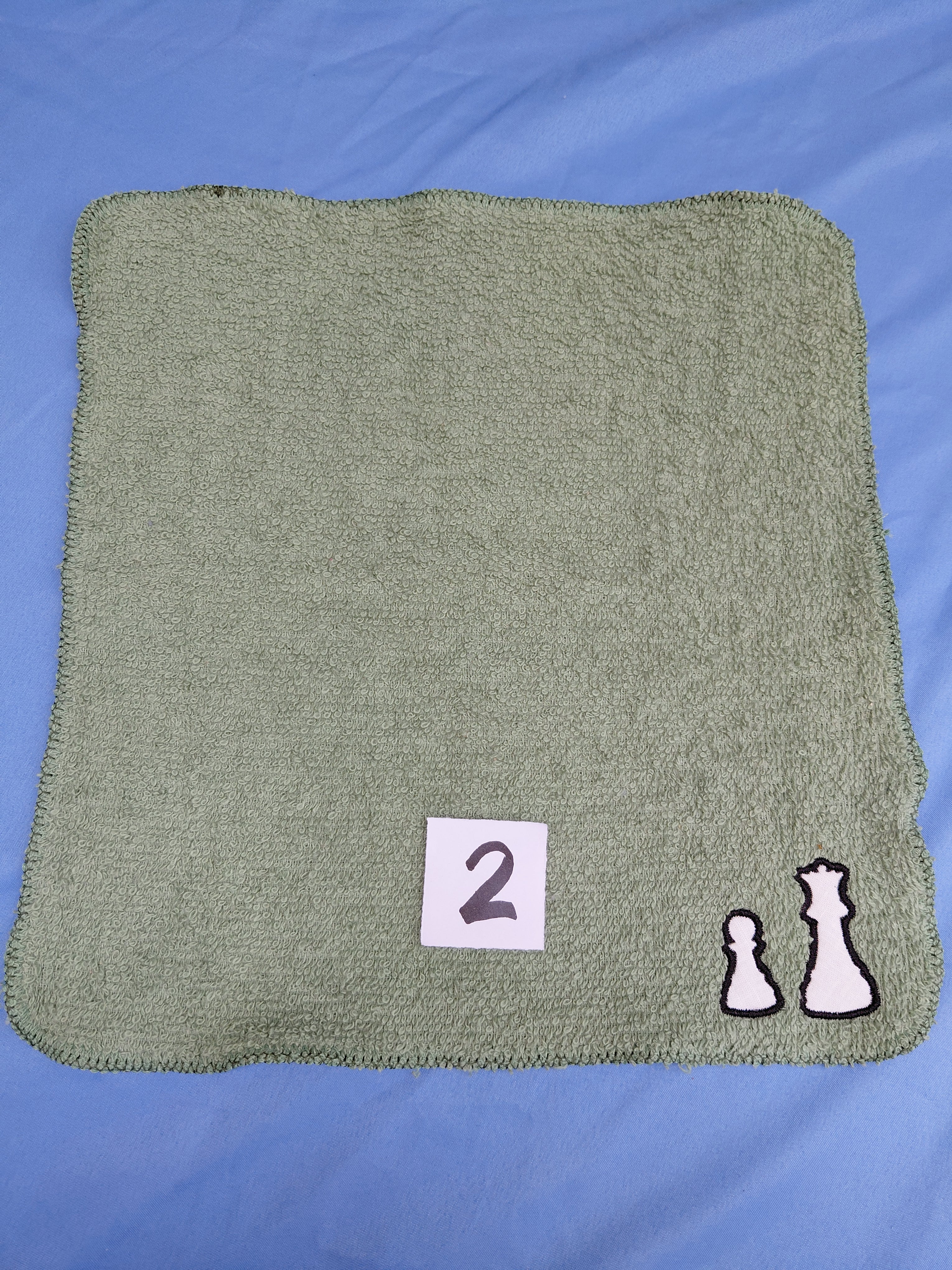 Green washcloth with embelished chess piece symbols .